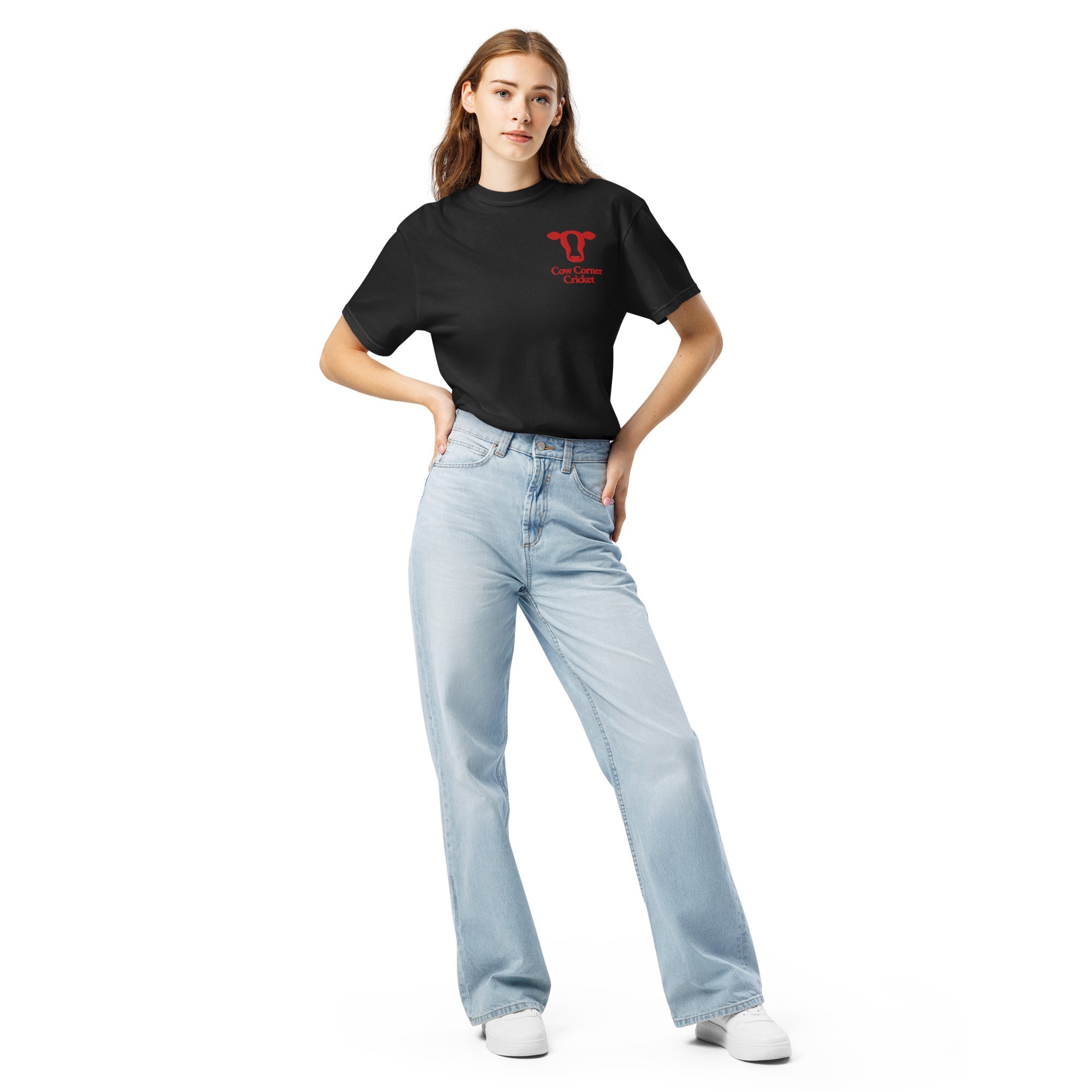 Woman wearing a black t-shirt with a small graphic and light blue jeans with a cow corner cricket logo
