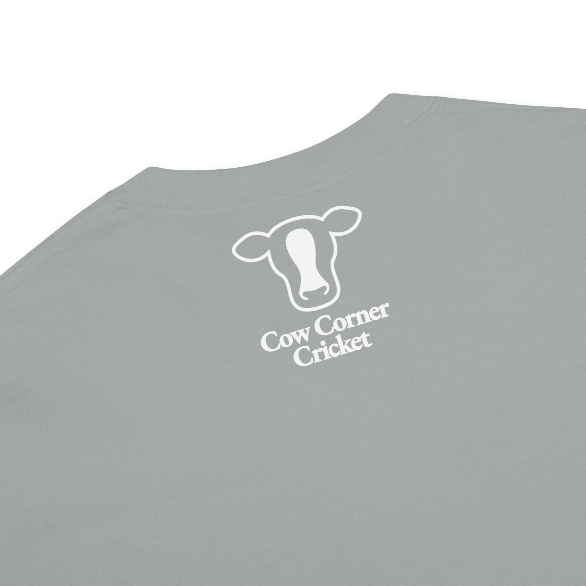 Close-up of a light gray t-shirt, printed with a white outline of a cow head and the text 'Cow Corner Cricket'.