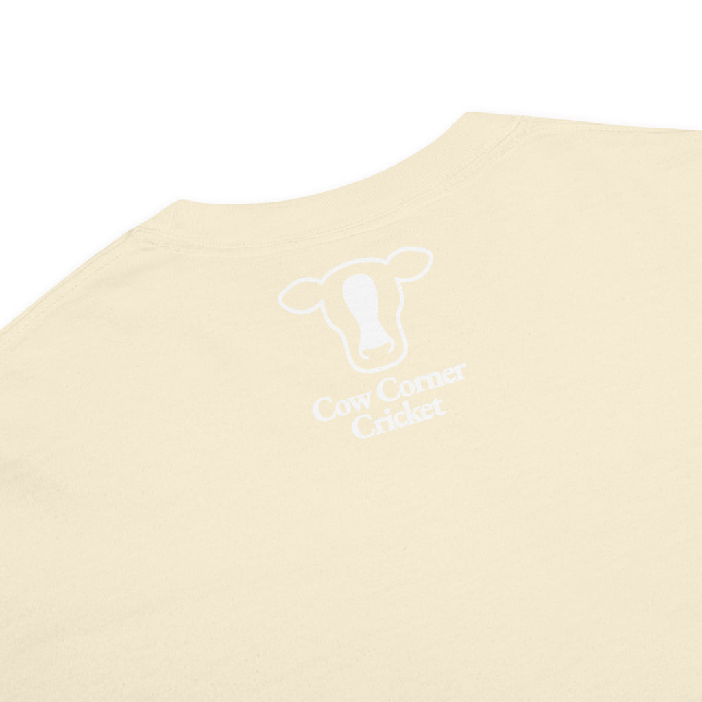 A close-up of a cream-colored t-shirt  and a white graphic print of a cow head outline with the text 'Cow Corner Cricket' underneath.