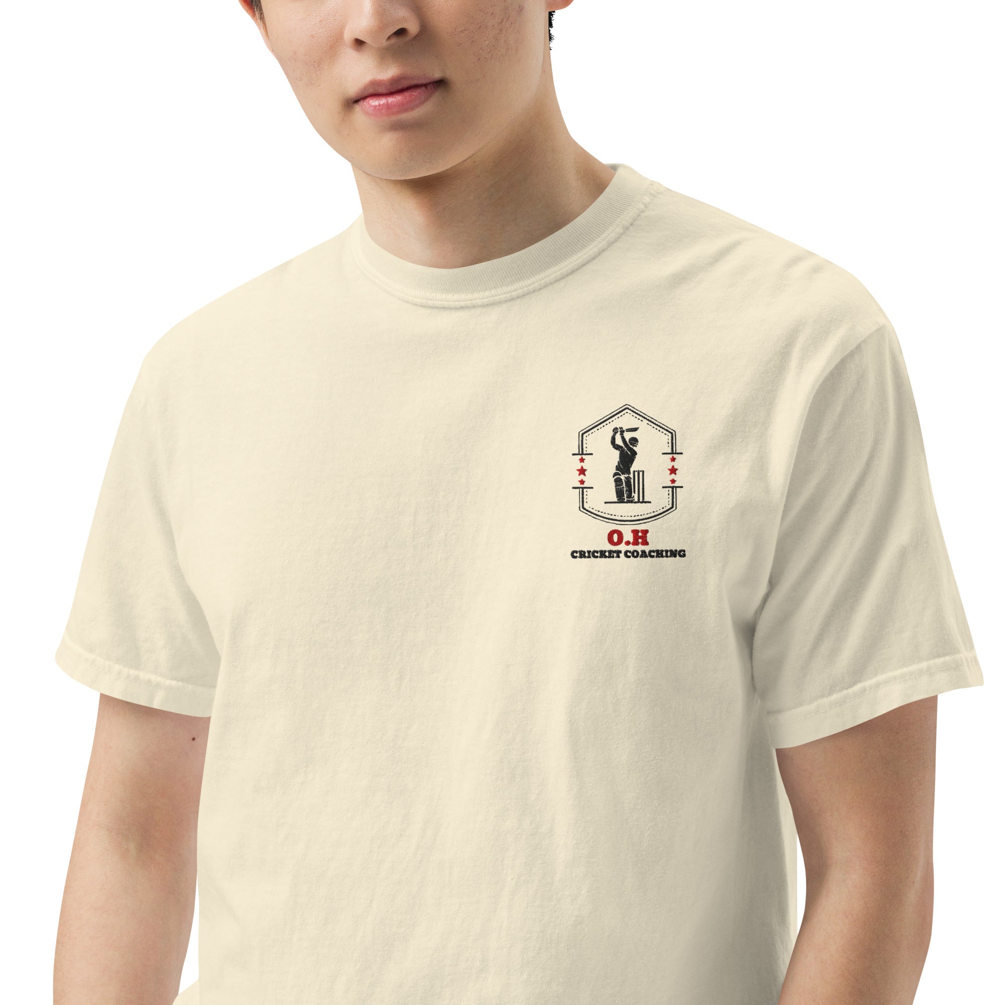 Person wearing a beige t-shirt with a logo on the chest