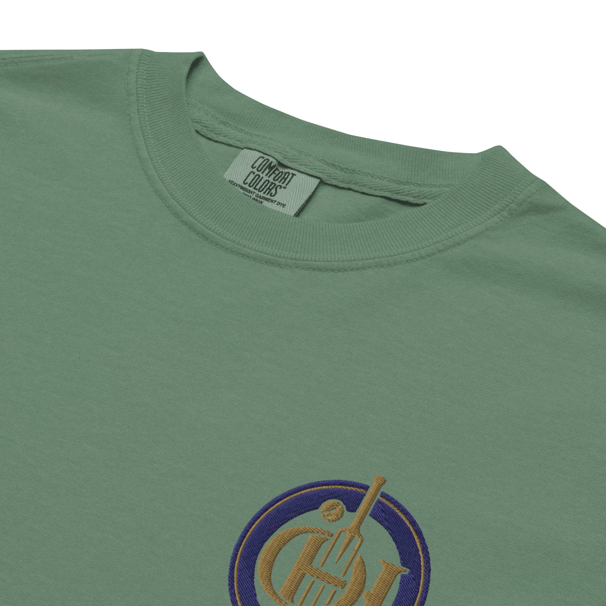 Close-up of a green t-shirt and a small circular graphic on the chest featuring a gold and purple instrument design.