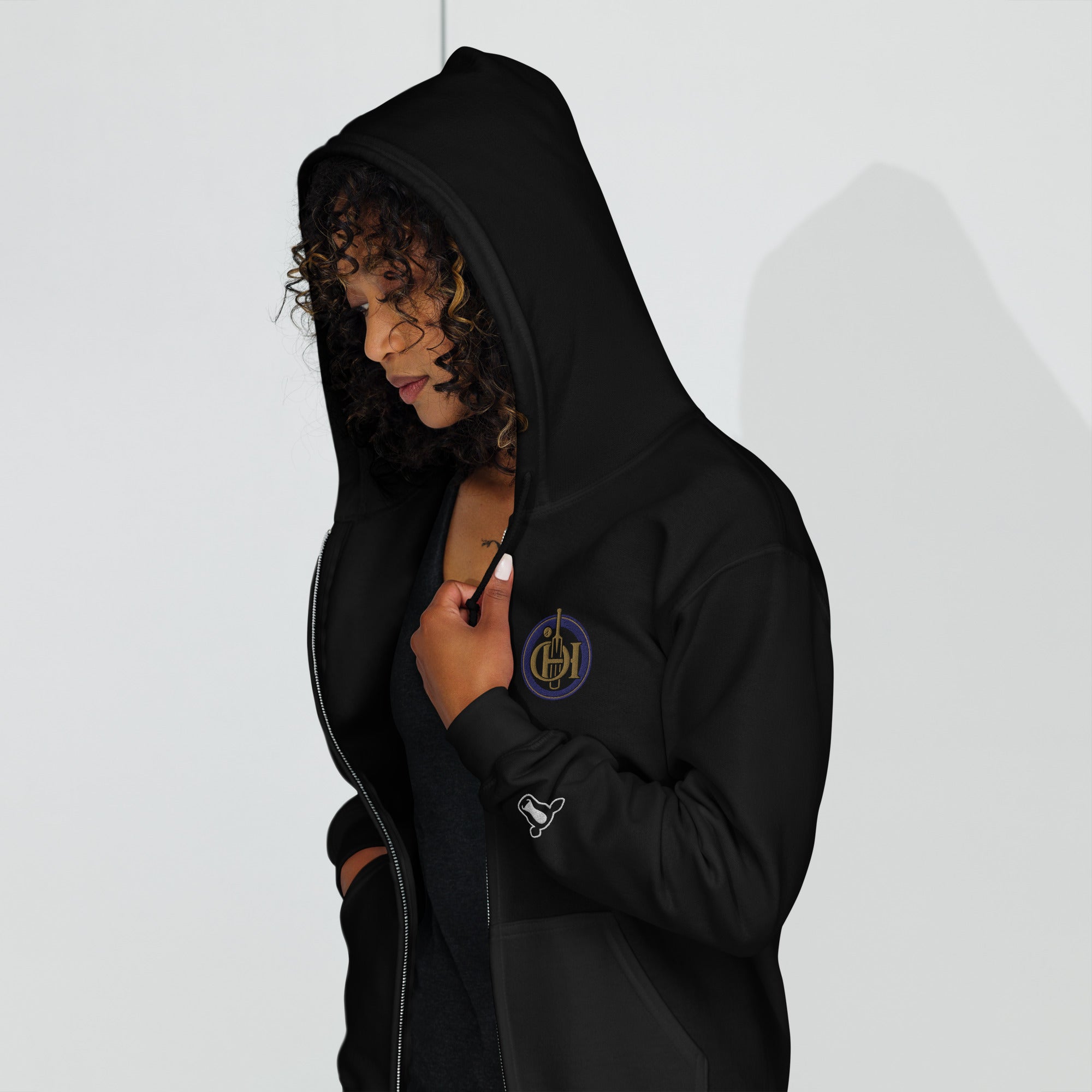 Person wearing a black hoodie with a gold emblem on a white background