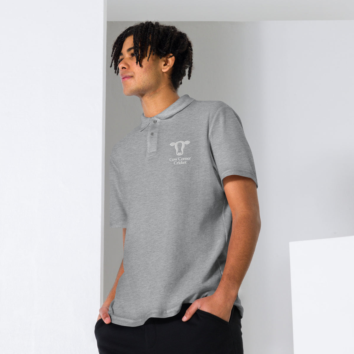 Person wearing a gray polo shirt with a Cow corner cricket logo on chest
