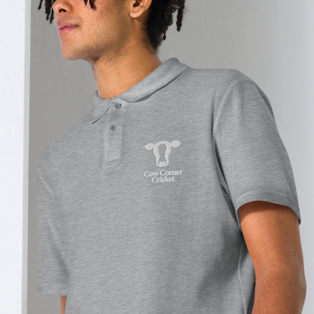 A man wearing a heather gray short-sleeve polo shirt with Cow Corner Cricket logo on the chest
