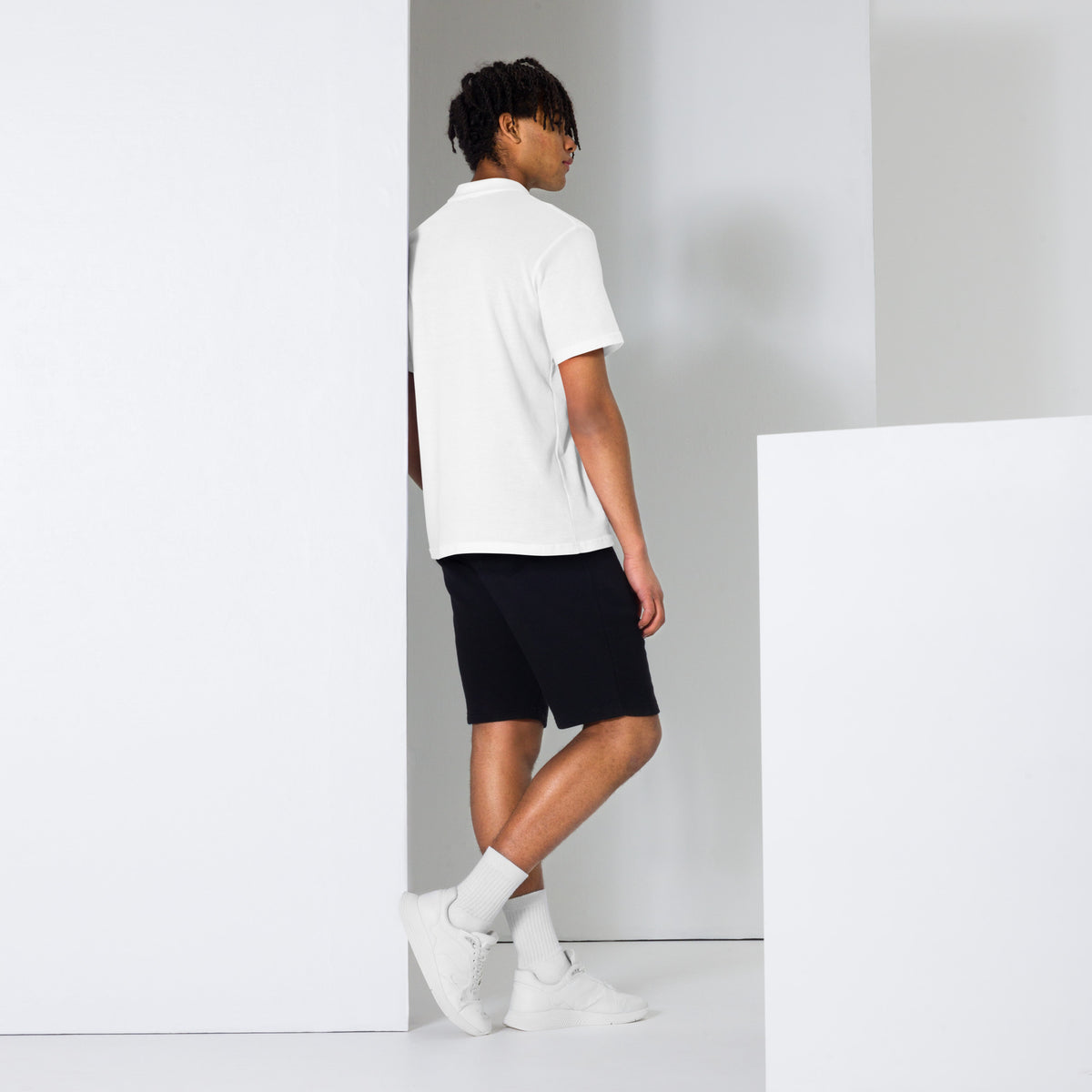 Person wearing a white polo shirt, black shorts, and white sneakers